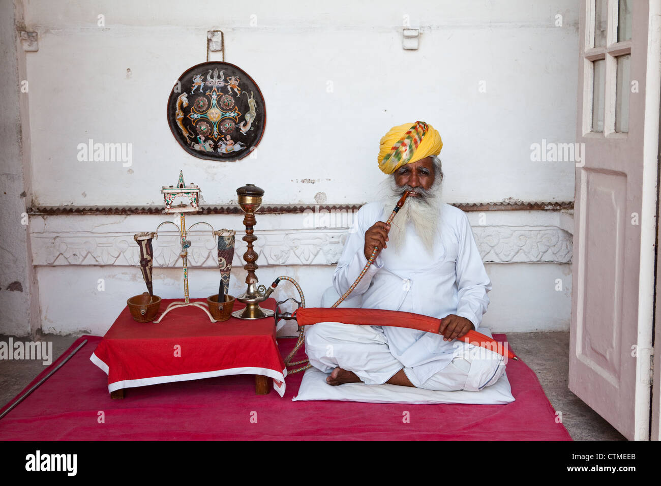 Alten indischen Mann in Turban Rauchen von Wasserpfeifen Rohr Mehrangarh Fort, Jodhpur Stockfoto