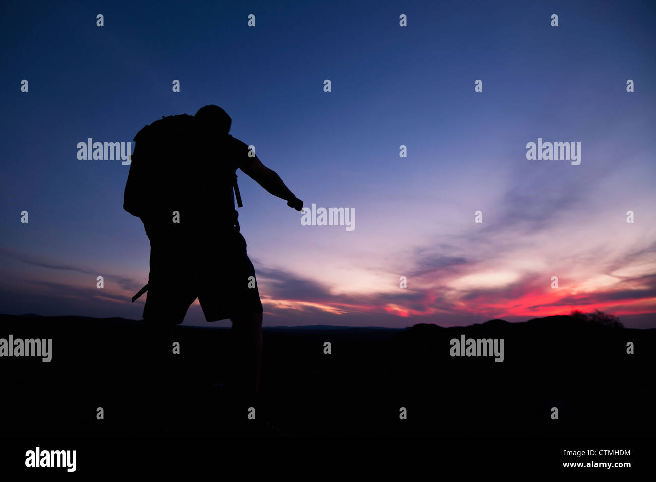 Wanderer zeigt in Richtung Horizont als das letzte Licht der Sonnenuntergang verblasst Stockfoto