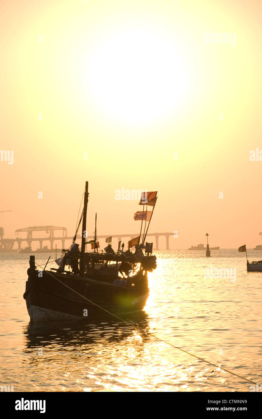 Silhouette einer Fähre während des Sonnenuntergangs - Mumbai, Indien. Bau von Worli Sea Link im Hintergrund Stockfoto