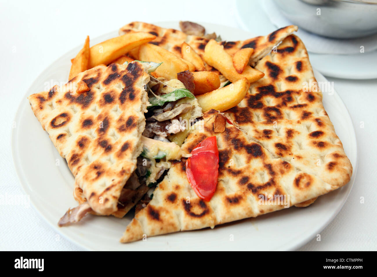 Eine Calzone-Stil bedeckt Pita Torte, Chicken-Souvlaki mit Fleisch, Salat und Käse, serviert mit Französisch gebratene Kartoffelchips Stockfoto