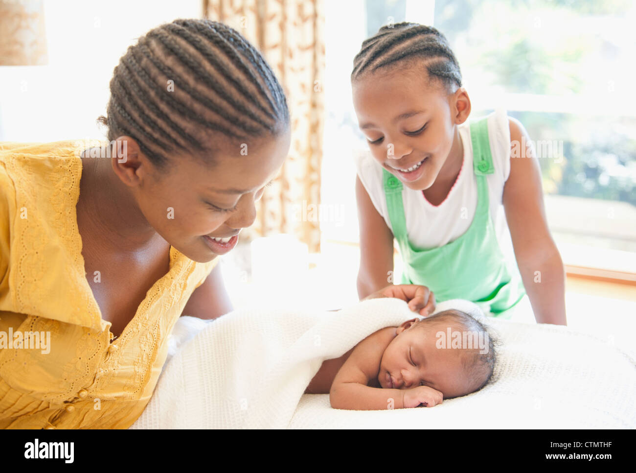 Mutter und junges Mädchen wachen über Neugeborene schlafen auf Bett in Johannesburg, Südafrika Stockfoto