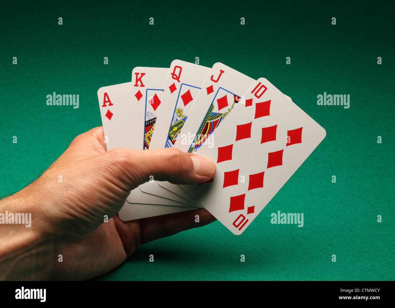 Eines Mannes Hand mit Spielkarten am grünen Tisch. Ein Royal Flush von Diamanten in das Spiel von Poker Stockfoto