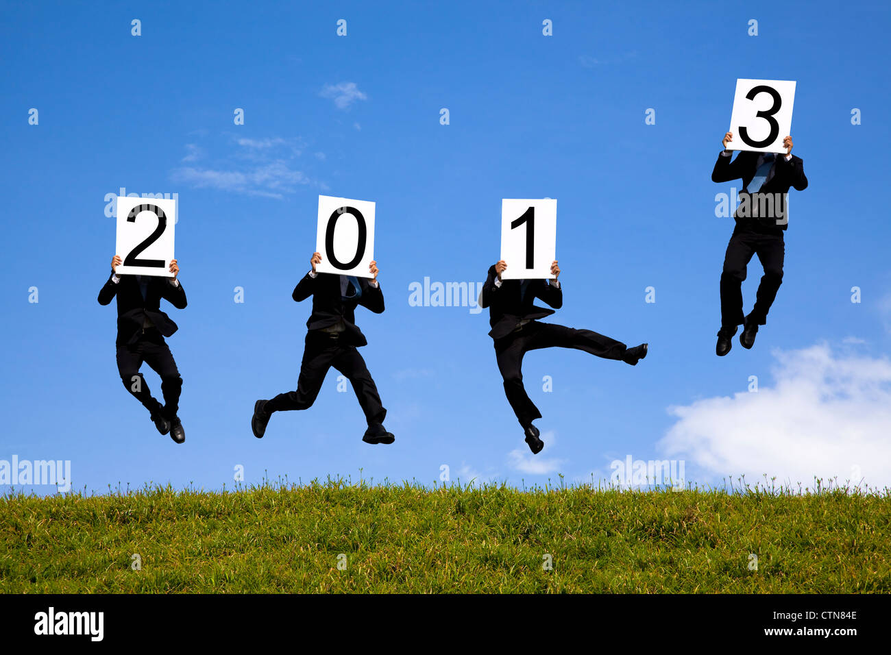 Geschäftsmann hält 2013 und springen auf der grünen Wiese Stockfoto