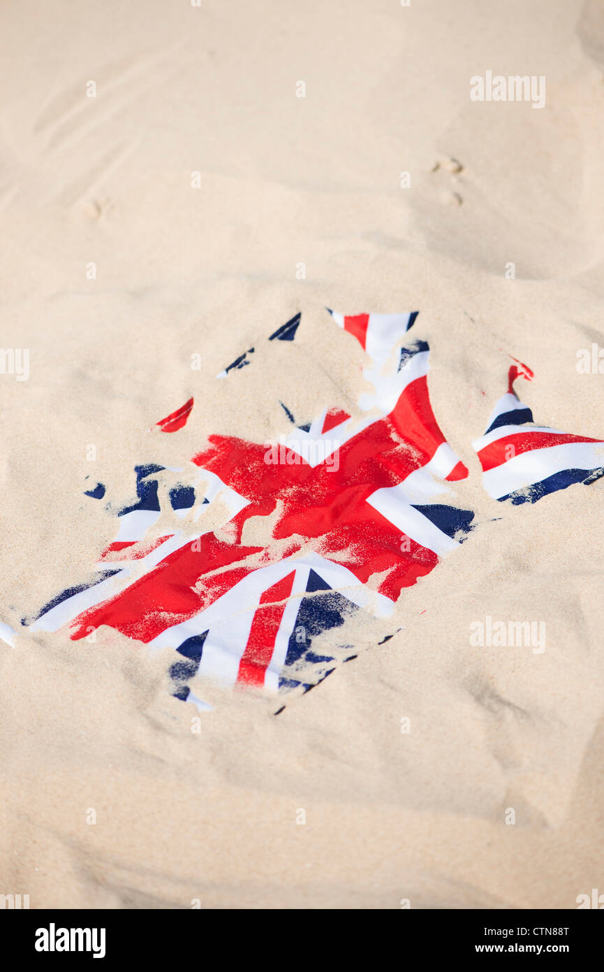 Union Jack-Flagge bedeckt im Sand am Strand Stockfoto