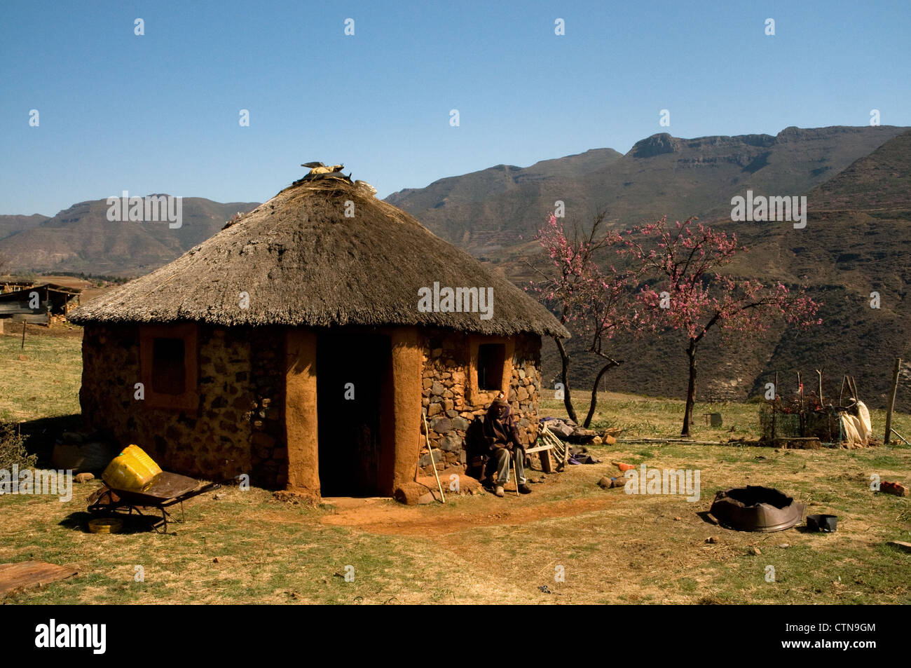 verletzten Hirte sitzend vor einem Rondavel Haus in Malealea Dorf, Lesotho, Afrika Stockfoto