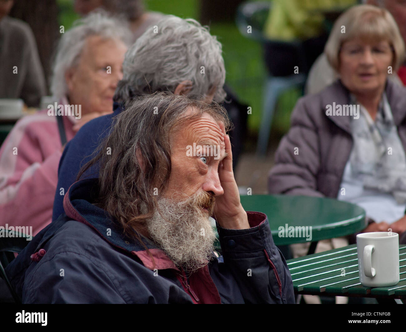 Ein Mann sitzt mit einer Tasse Tee im Pavilion Gardens, Brighton. Stockfoto