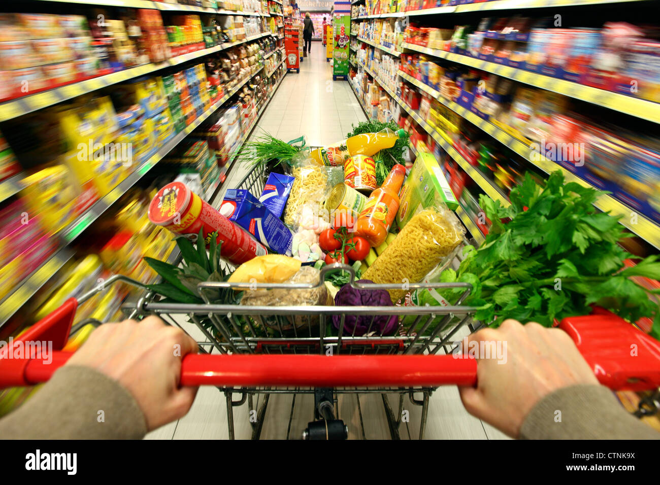 Essen Halle, voller Einkaufswagen wird durch einen Flur mit mehreren Nahrungsmitteln geschoben. Grosser Supermarkt, Self-Service. Stockfoto
