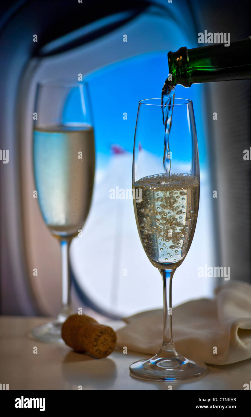 Französischen Champagner während des Fluges in Luxus-Kabine mit Fenster und Flugzeug Flügel hinter gießen Stockfoto