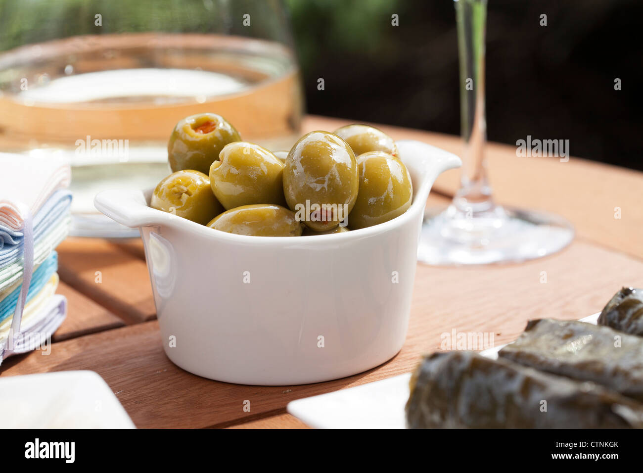 Grüne Oliven gefüllt mit roter Piment in kleinen weißen Schüssel. Stockfoto