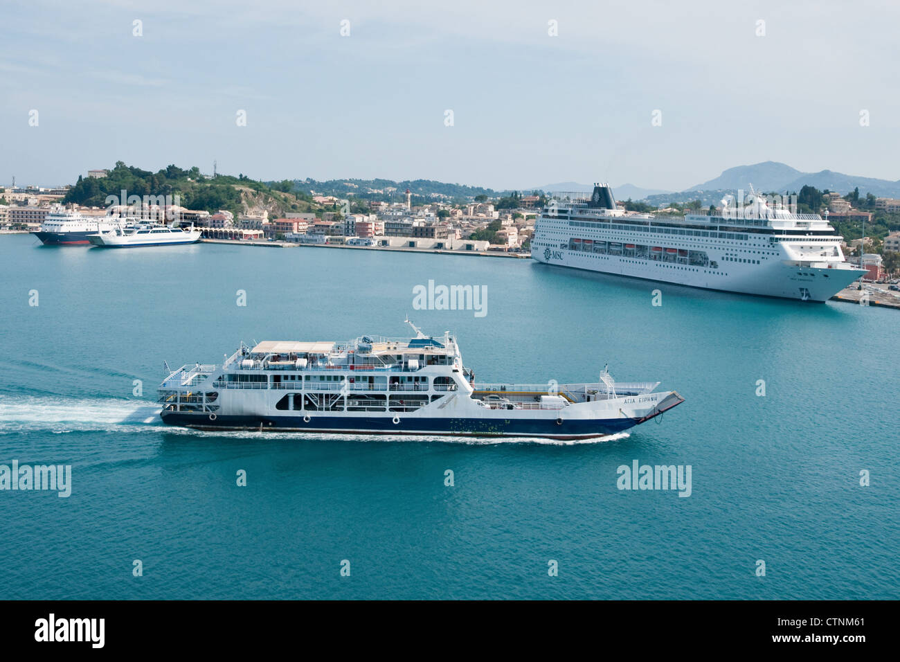 Eine Autofähre geht das Kreuzfahrtschiff MSC Armonia, wie es nähert sich seinen Liegeplatz im Hafen Kerkyra, Korfu, Griechenland Stockfoto