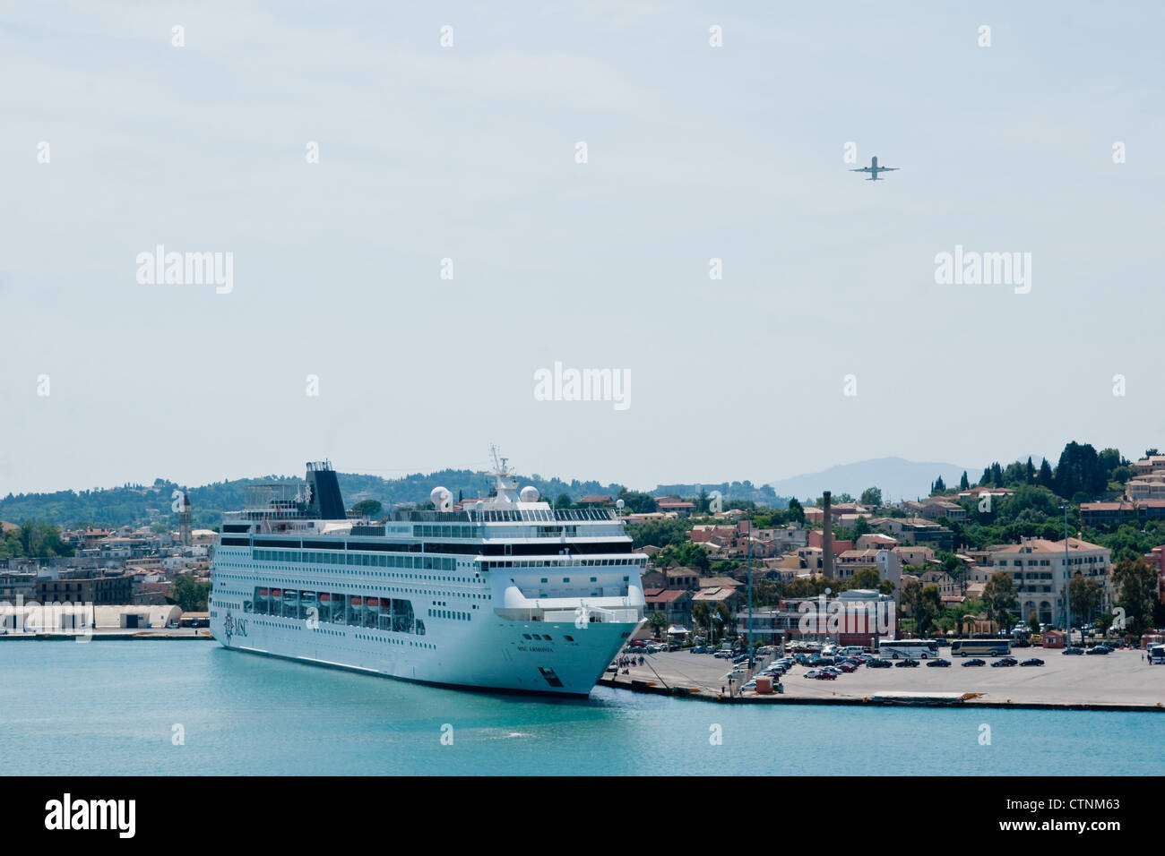 Ein Flugzeug vom Flughafen Korfu geht über das Kreuzfahrtschiff MSC Armonia vertäut im Hafen Kerkyra Corfu Stockfoto