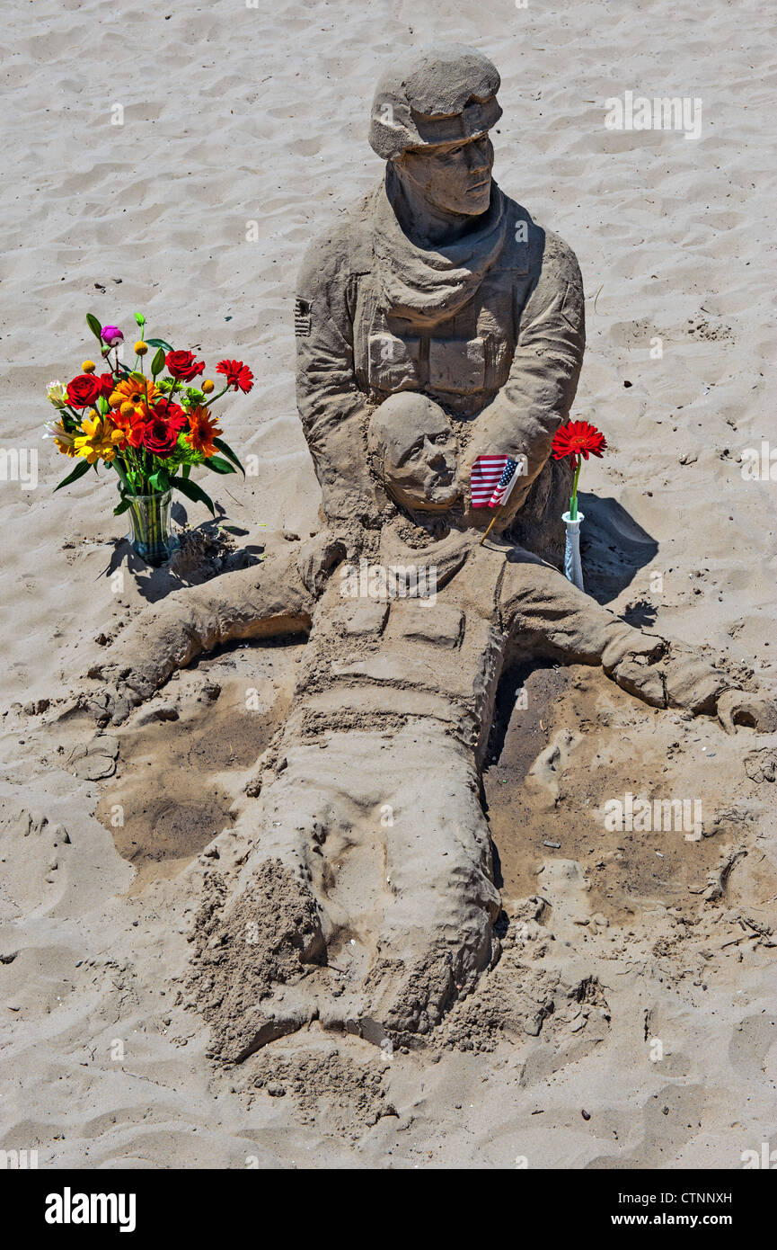 US Marine hergestellt aus Sand, hält einen kritisch Verwundeten Soldat am Arlington West Denkmal. East Beach, Kalifornien Stockfoto