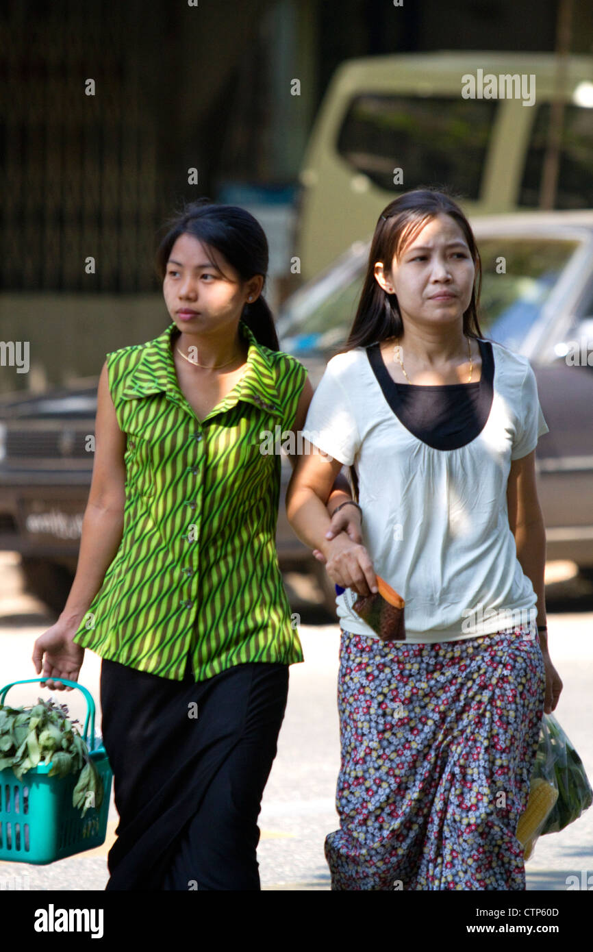 Birmanische Frauen gehen Arm in Arm auf der Straße in Yangon (Rangoon), Myanmar (Burma). Stockfoto