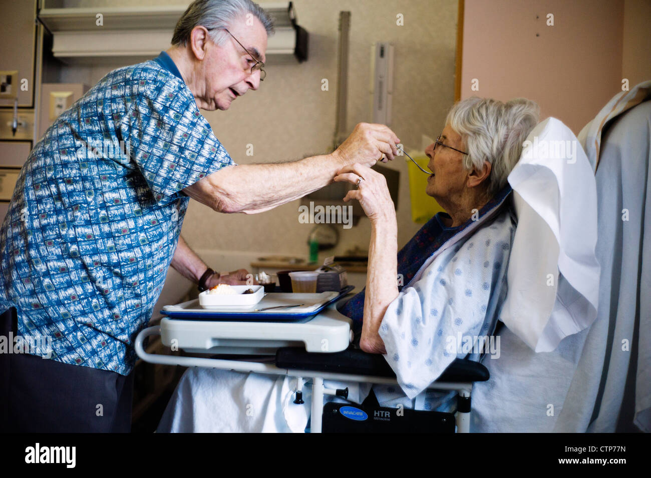 Alter Mann Fütterung alte Frau im Krankenhausbett. Stockfoto