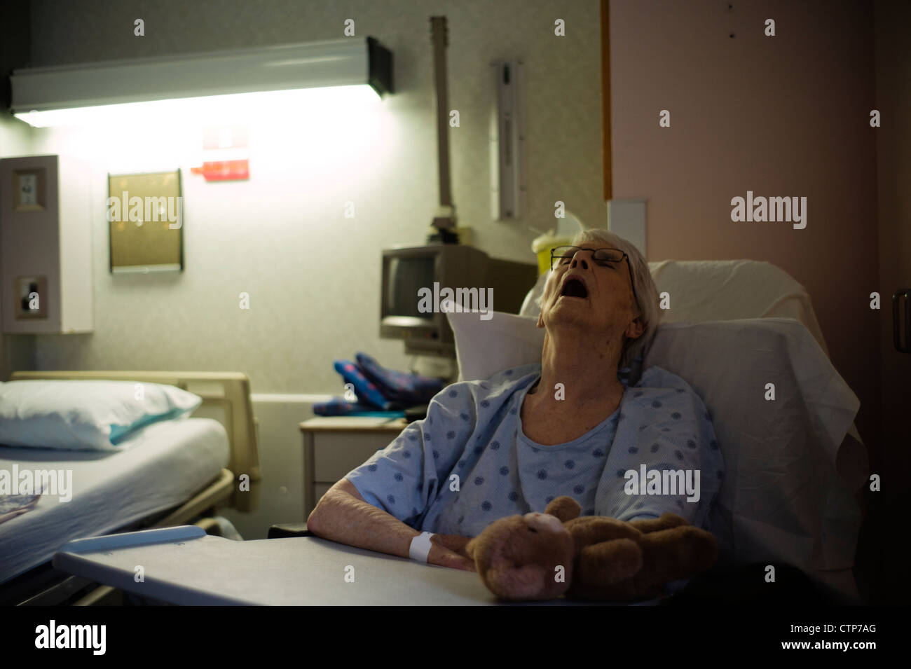 Alte Frau schlafend im Krankenhausbett aufgestützt. Stockfoto