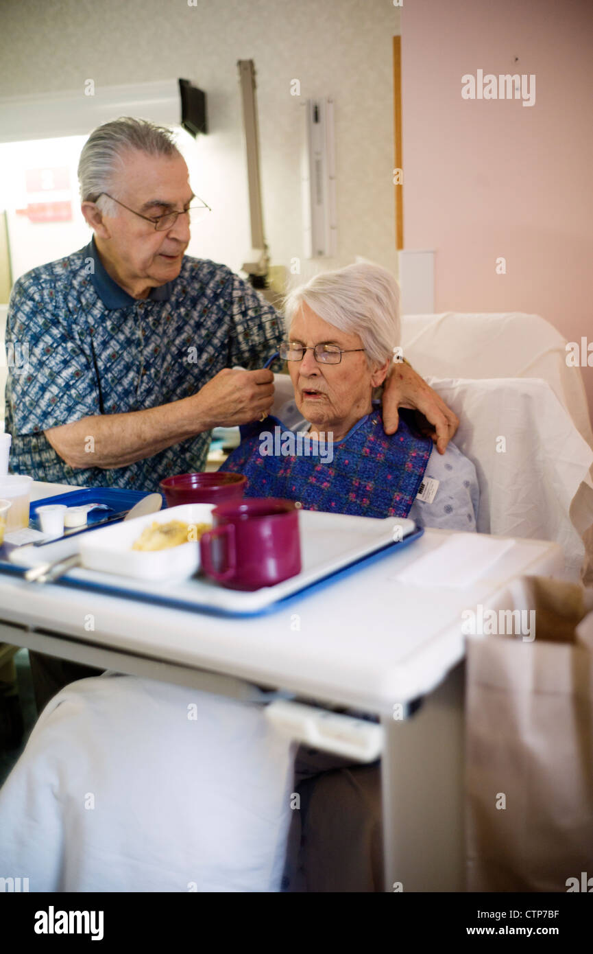 Alter Mann Fütterung alte Frau im Krankenhausbett. Stockfoto