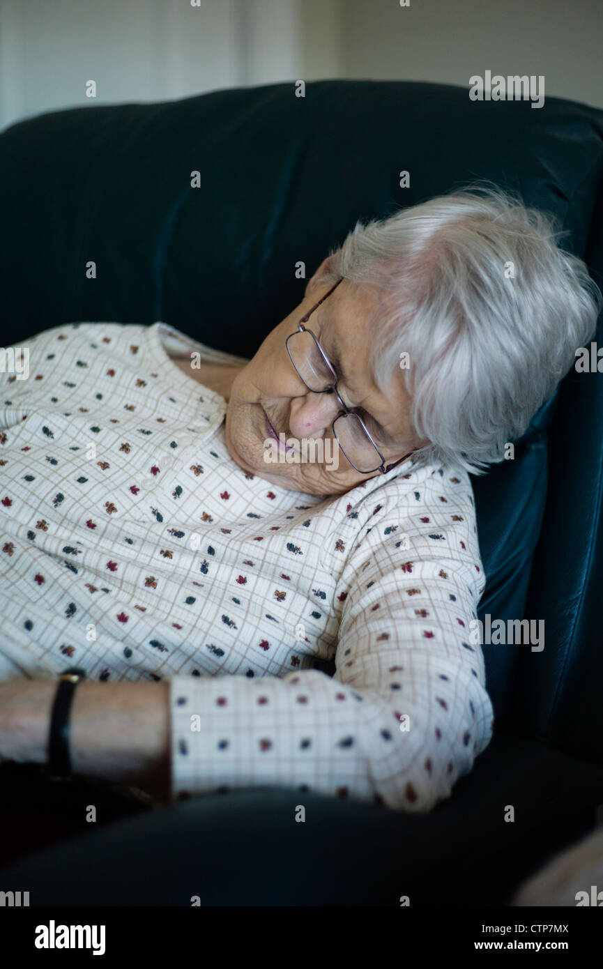 Alte Frau brach über schlafend im Sessel Stockfoto