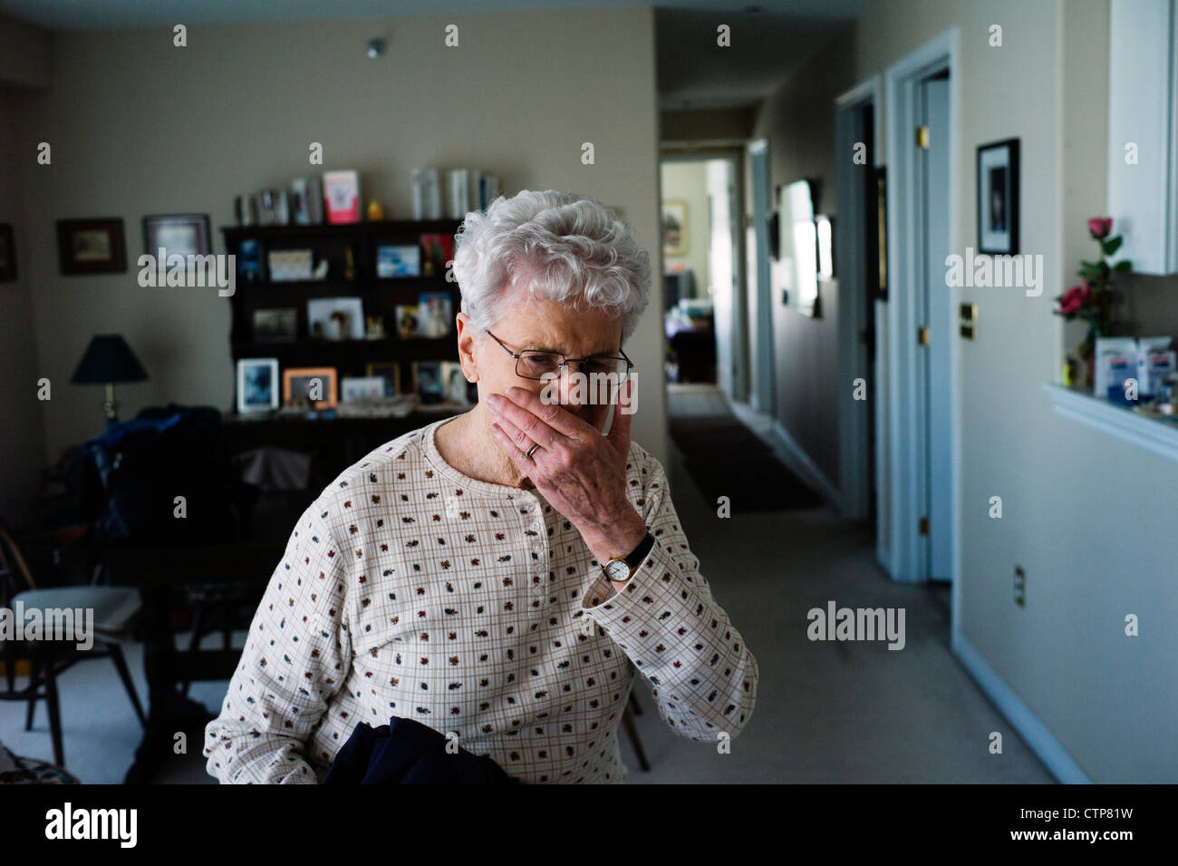 Alte Frau steht umklammert Geldbörse zu Hause. Stockfoto