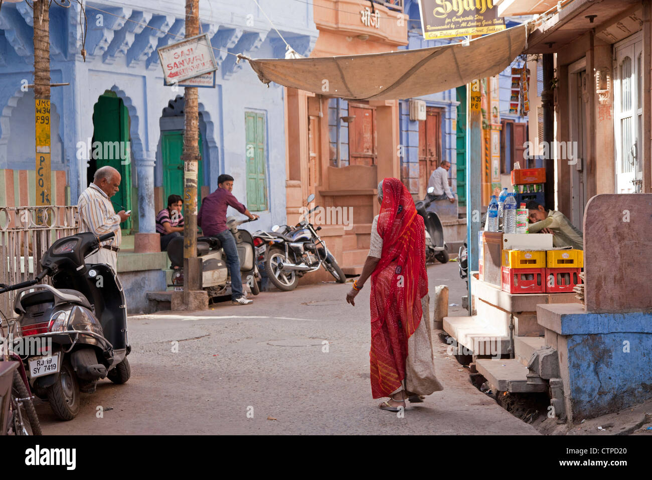 Straßenszene mit Indianerin gekleidet im roten Sari in die blaue Stadt Jodhpur, Rajasthan, Indien Stockfoto