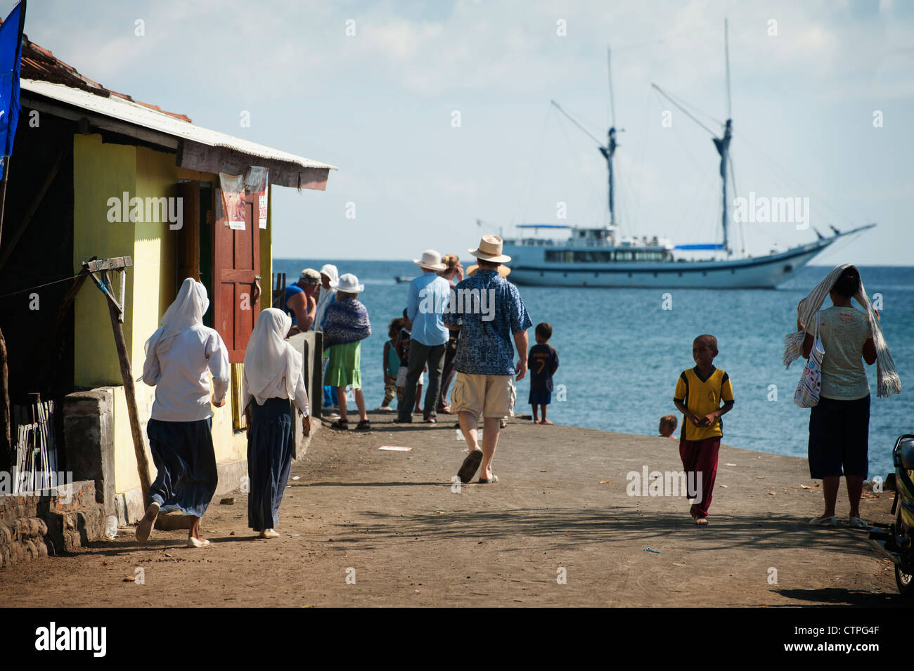 Touristen betreten der muslimischen Dorf Komodo auf der Insel Komodo mit dem Segelboot "Ombak Putih" im Hintergrund. Indonesien Stockfoto