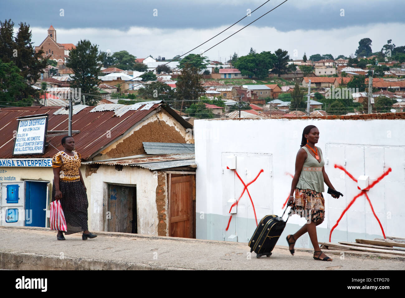 Täglichen Lebens Szene in Iringa, Tansania, Afrika. Zwei Frauen gehen auf die Straße Bürgersteig mit einem Stadtpanorama zu sehen. Stockfoto
