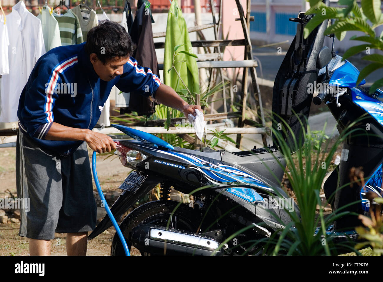 junger Mann Waschen sein Motorrad im kleinen Dorf Java Indonesien Stockfoto