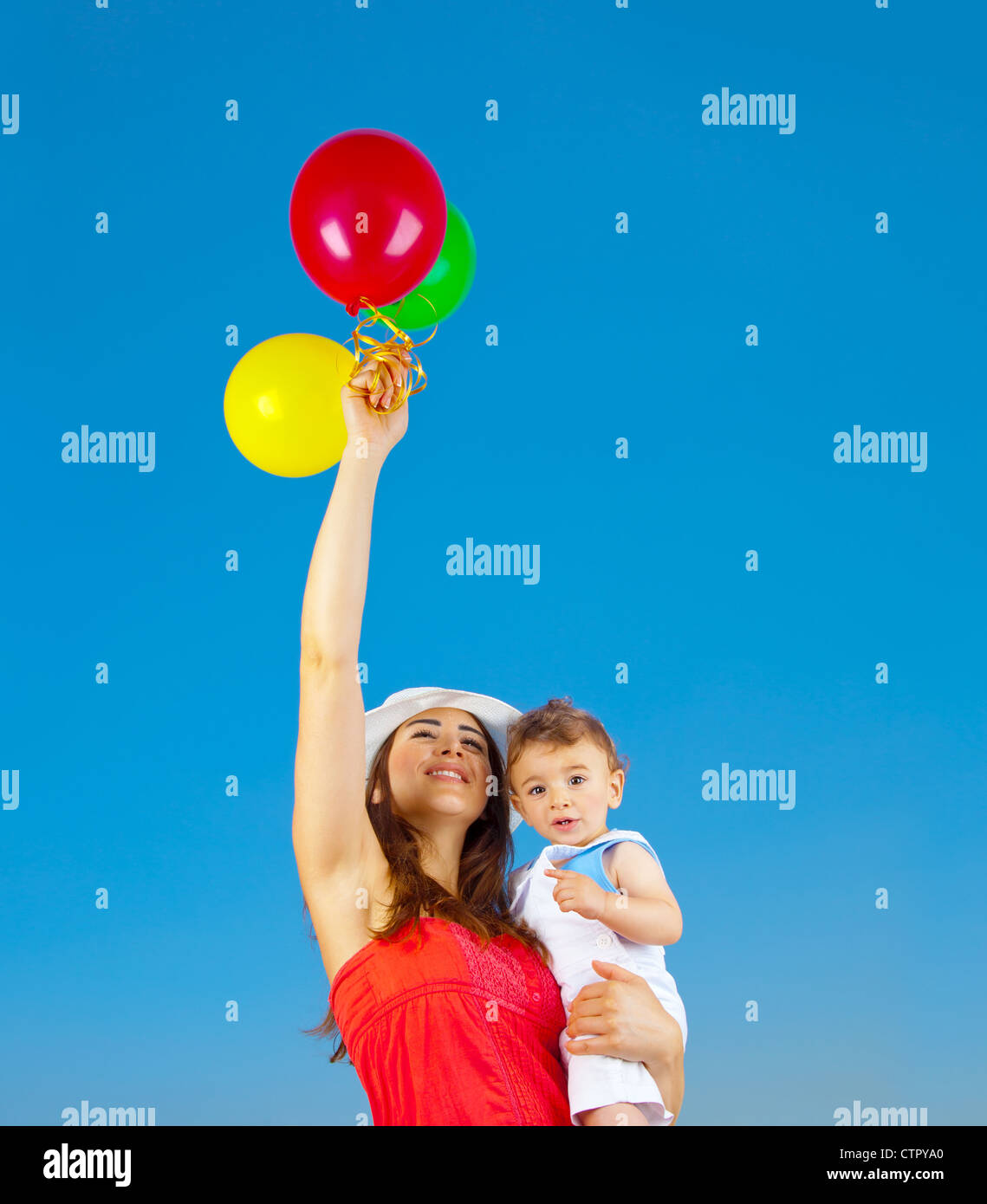 Glückliche Familie mit bunten Luftballons über blaue Himmelshintergrund, Mutter und entzückenden Kind Baby Boy Spielen im freien Stockfoto