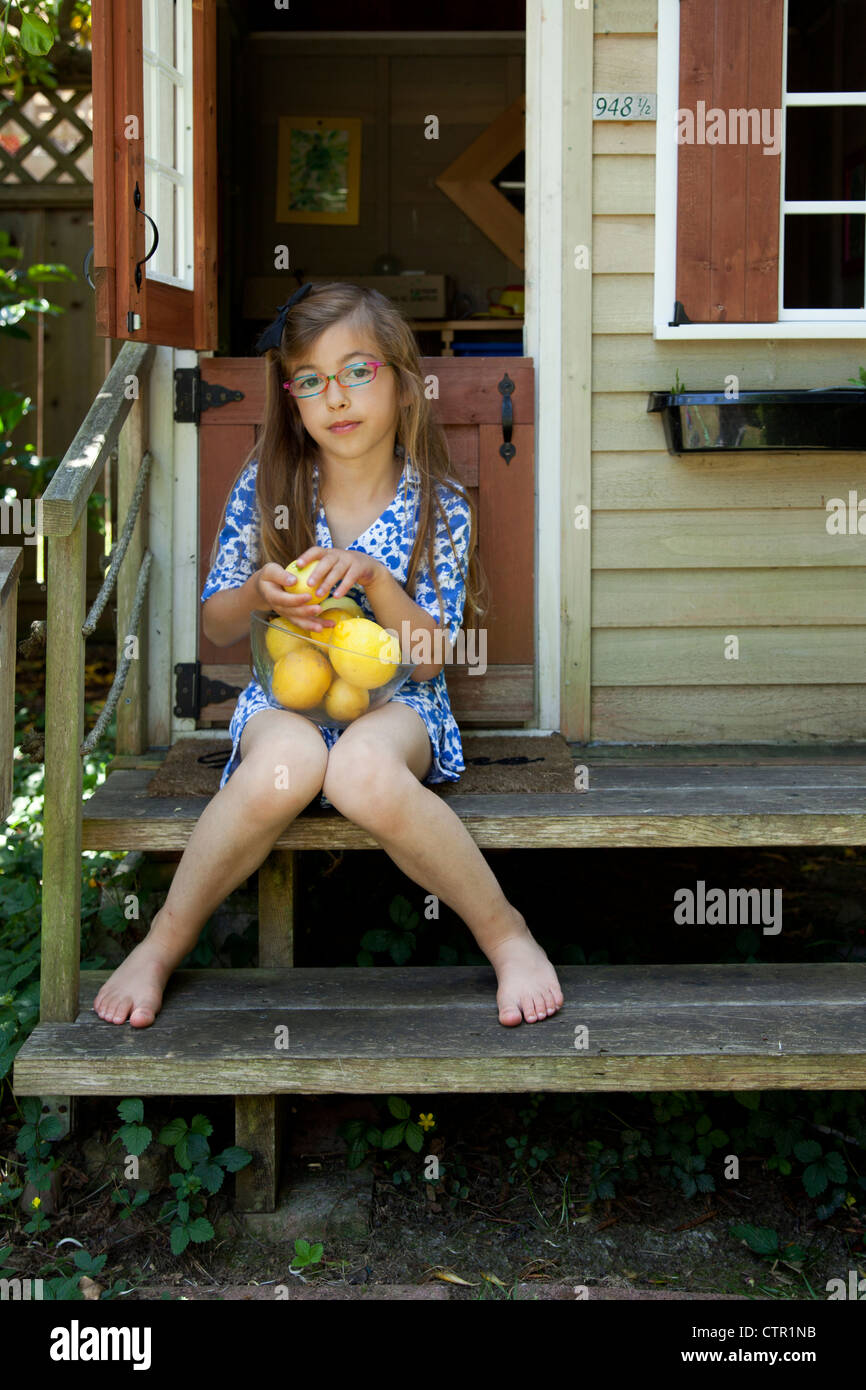 Ein kleines Mädchen mit einer Schale der Zitronen ist vor ihr Schauspielhaus. Stockfoto