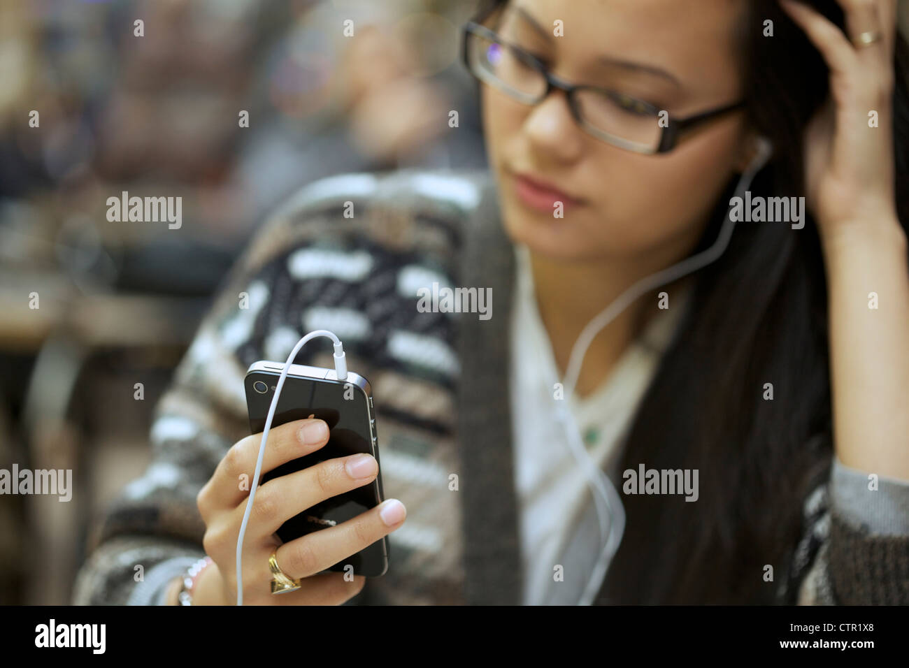 Junge Frau trägt Kopfhörer Musik hören mit ihrem Iphone 4 Stockfoto