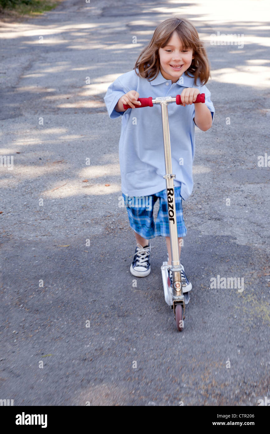 Ein kleines Mädchen reitet auf ihrem Roller. Stockfoto