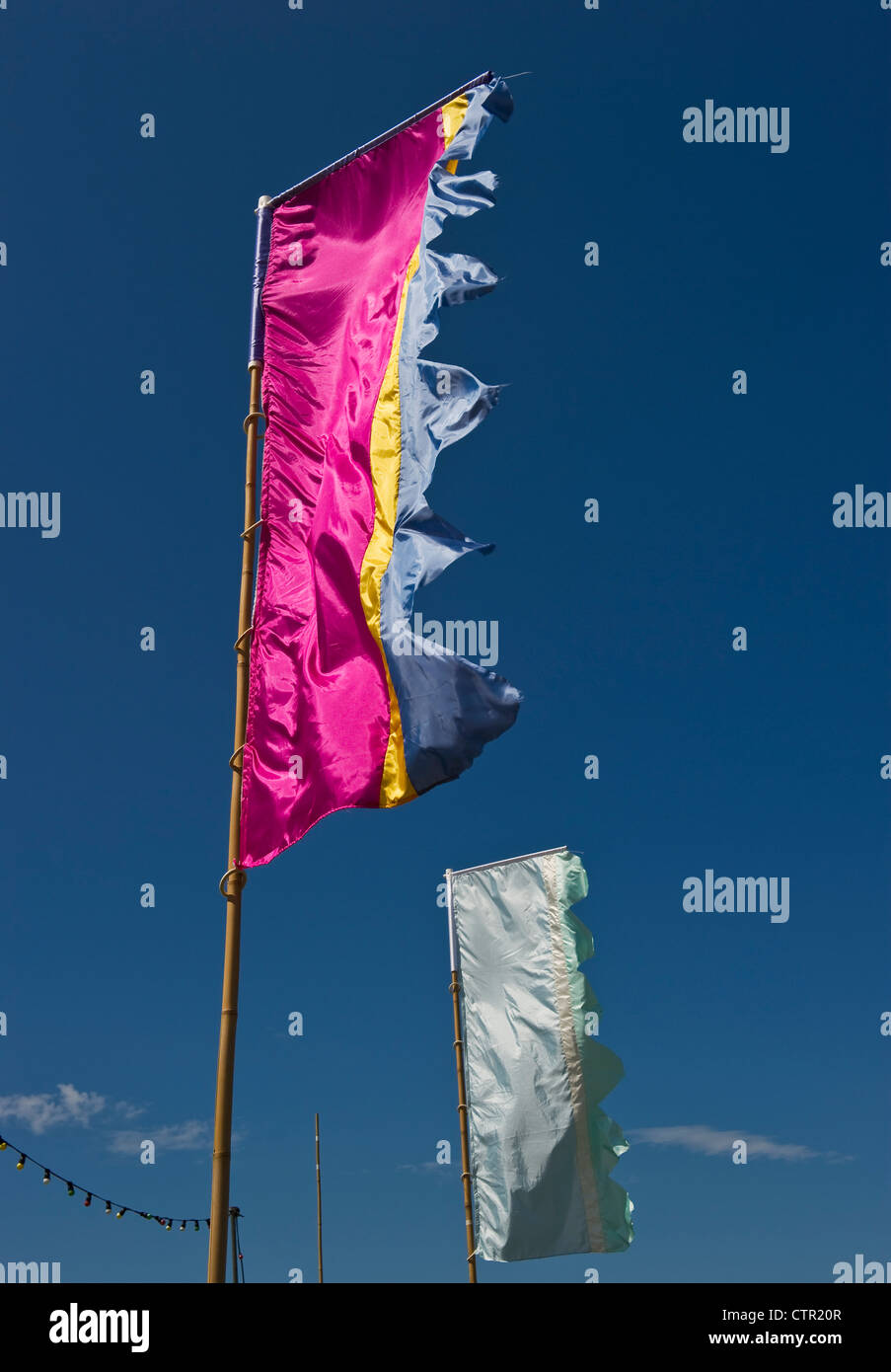 Bunte Flaggen fliegen im Sommer bei einem Musikfestival in Großbritannien gegen einen blauen Himmel Stockfoto