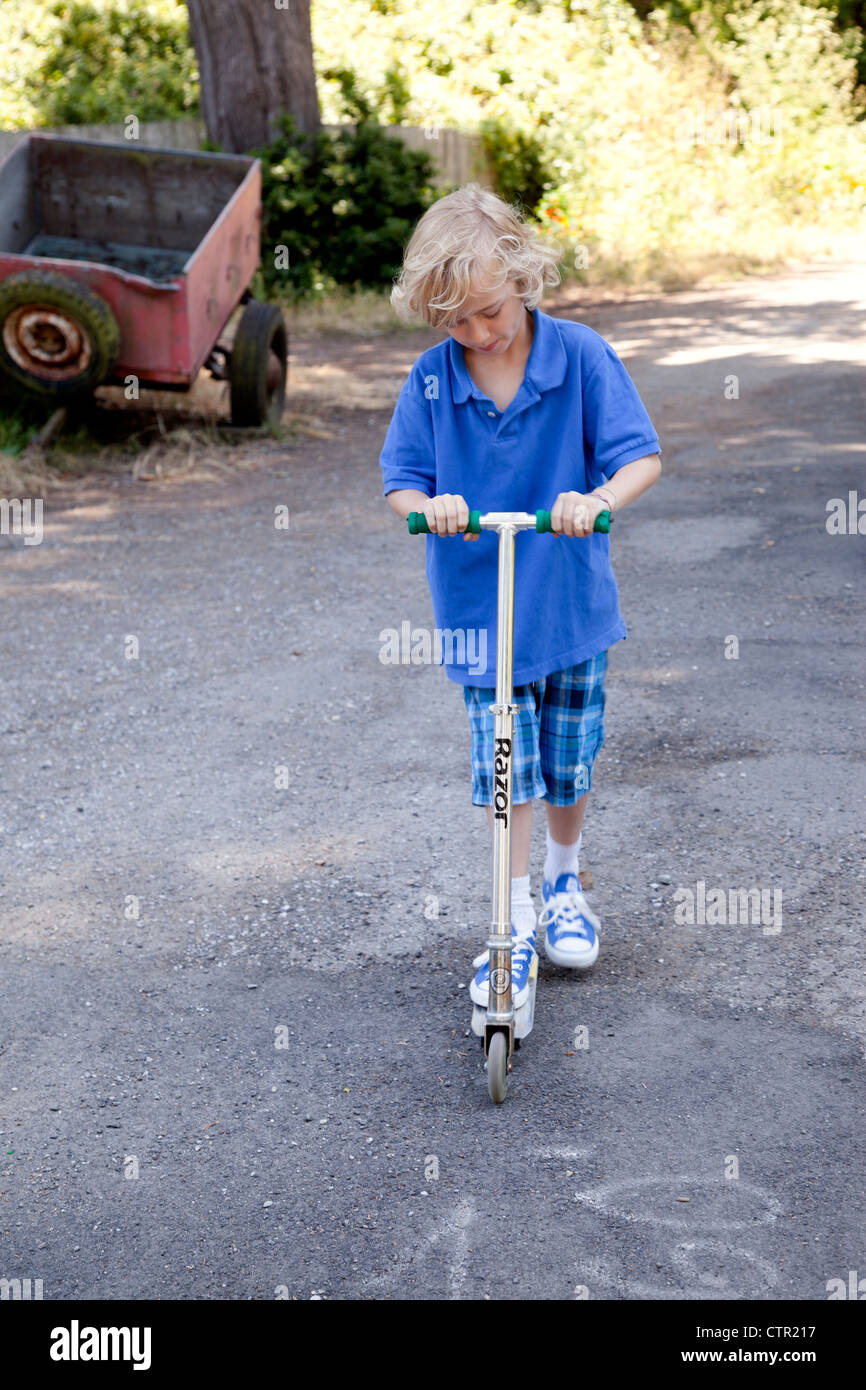 Junge draußen auf seinem Roller spielen. Stockfoto