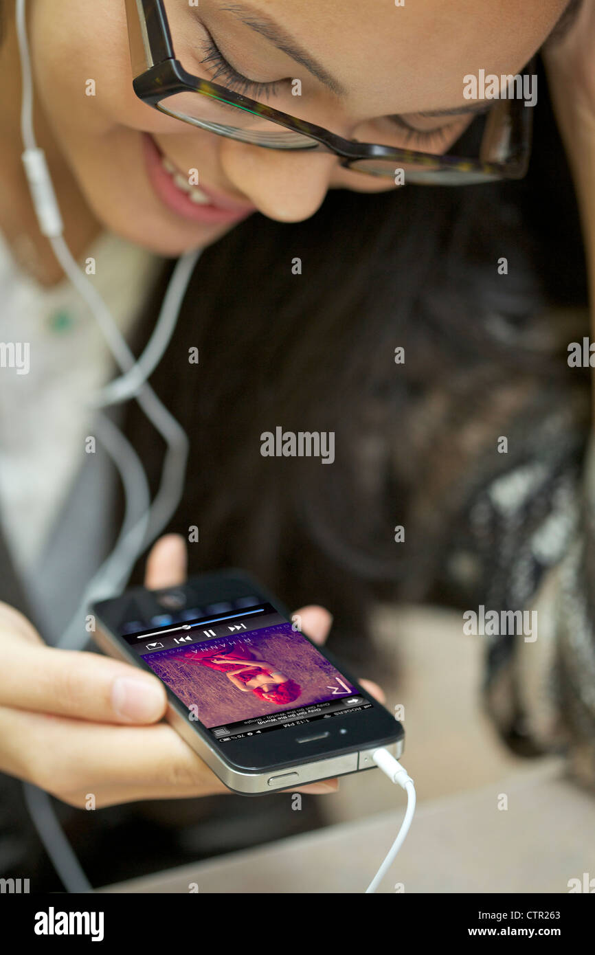 Lächelnde junge Frauen tragen Kopfhörer Musik hören mit ihrem Iphone 4 Stockfoto