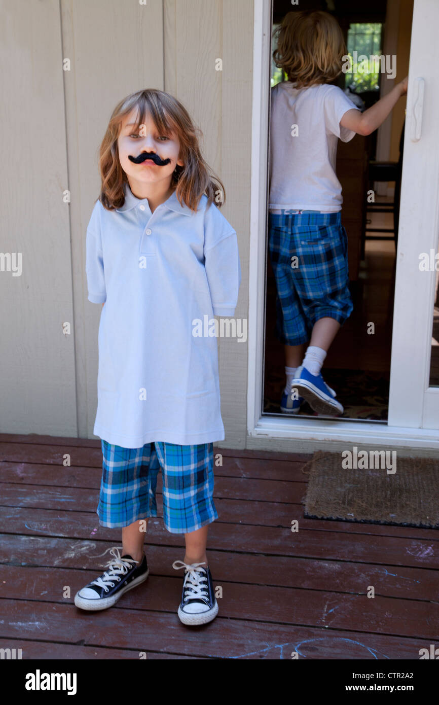 Ein kleines Mädchen steht auf dem Deck einen falschen Schnurrbart tragen. Stockfoto