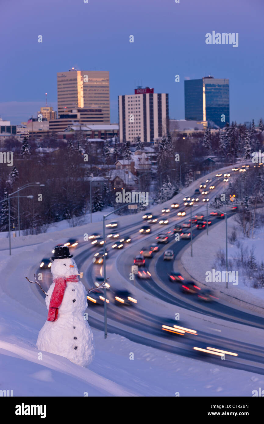 Blick auf den Verkehr und die Innenstadt von Anchorage mit einem Schneemann im Vordergrund, Yunan Alaska Winter. Digital verändert. Stockfoto