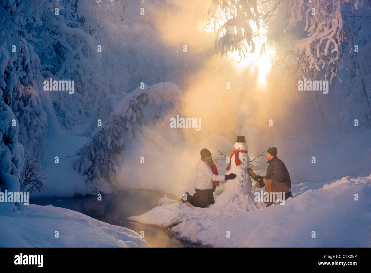 Mann Frau Schneemann in frostigen Wald Hintergrundbeleuchtung durch Sonnenstrahlen russische Jack Federn Park Yunan Alaska Winter bauen Stockfoto