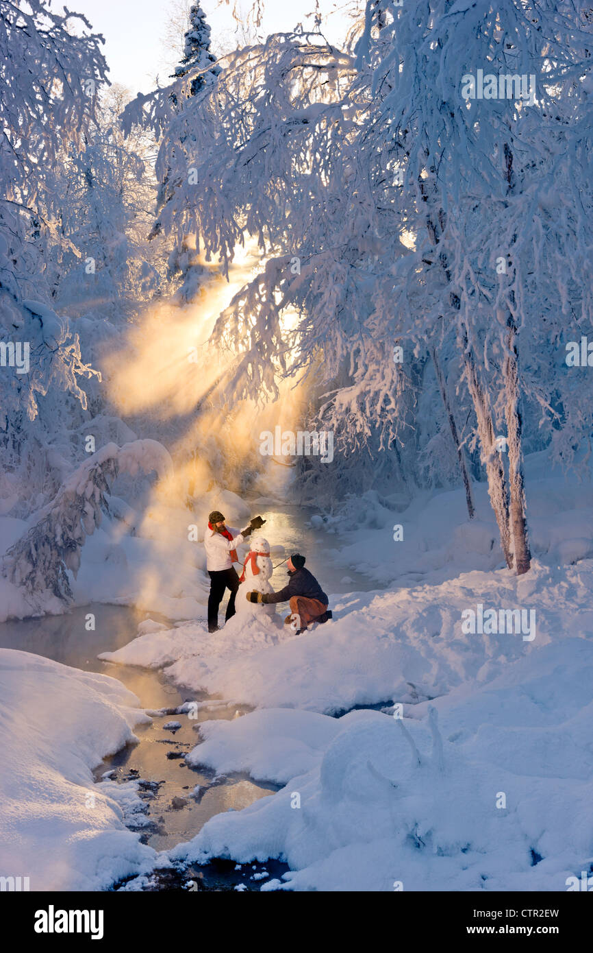 Mann Frau Schneemann in frostigen Wald Hintergrundbeleuchtung durch Sonnenstrahlen russische Jack Federn Park Yunan Alaska Winter bauen Stockfoto