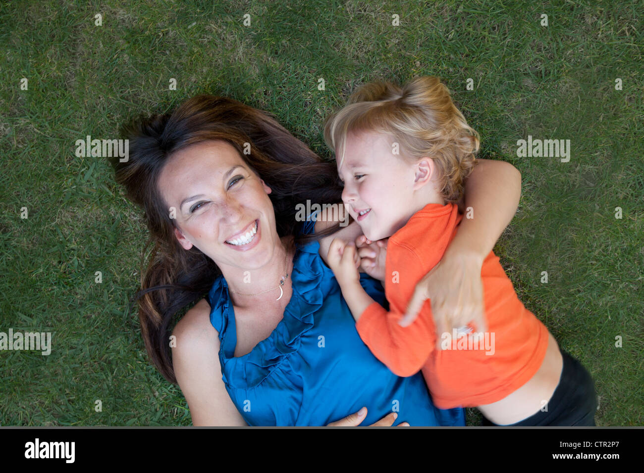 Mutter und Sohn liegen auf dem Rasen, Lächeln und lachen. Stockfoto
