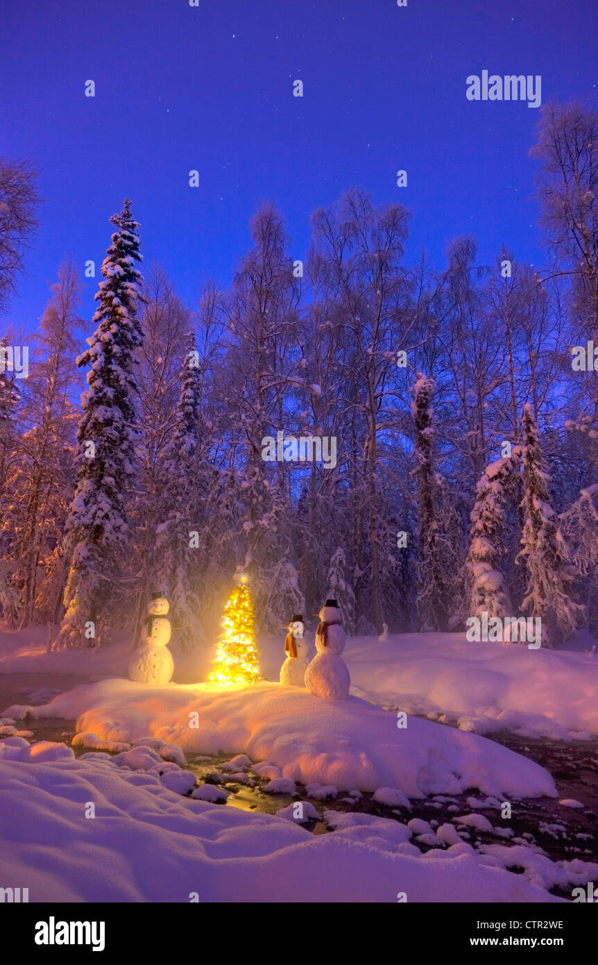 Schneemann Familie stehen nächsten Weihnachtsbaum auf Schnee bedeckte Insel in mittleren kleinen Bach in Raureif bedeckt Wald Dämmerung Stockfoto