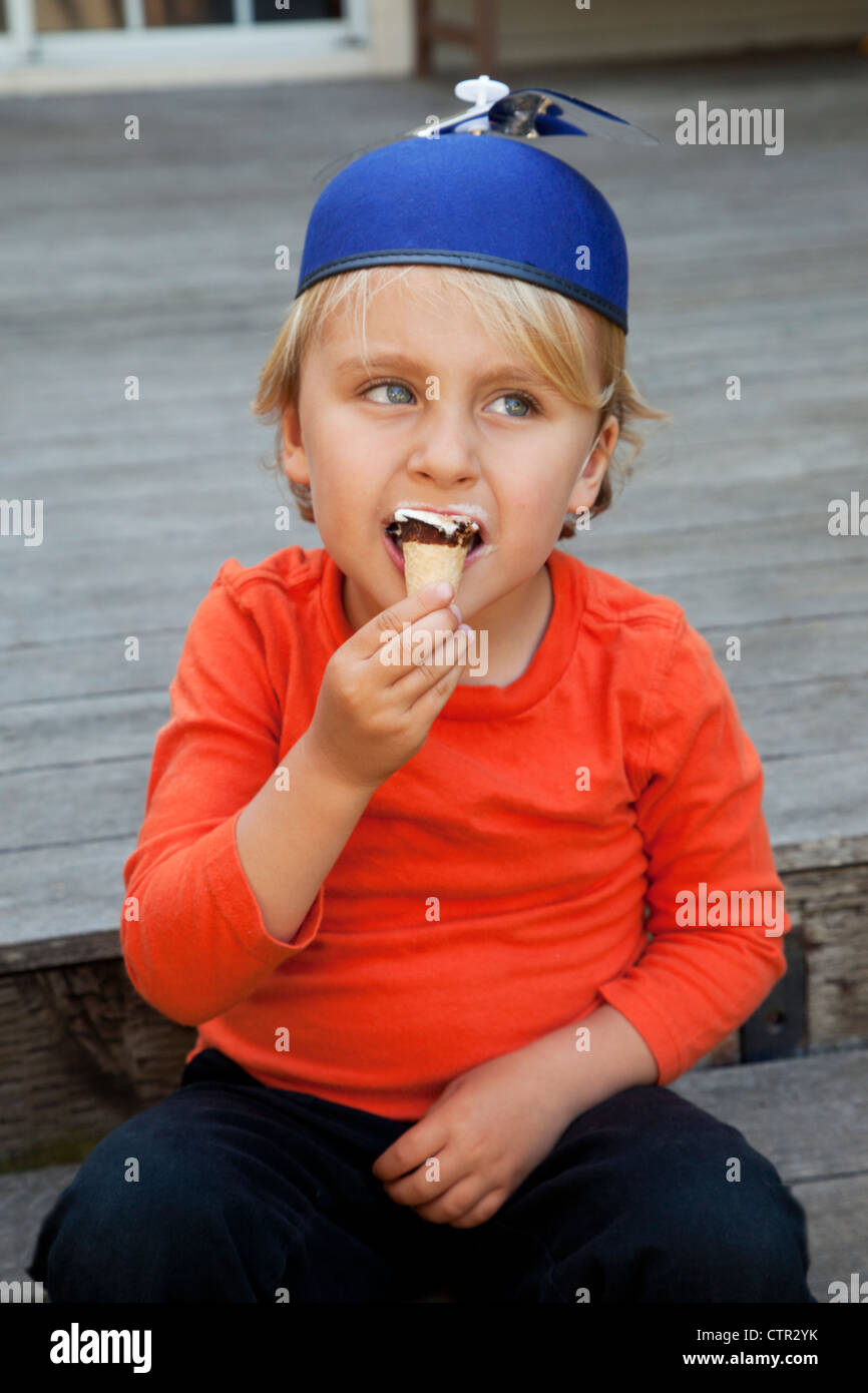 Ein Junge in einem Propeller Hut ist ein Eis essen. Stockfoto
