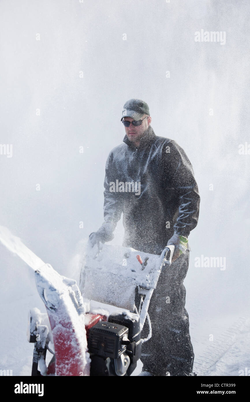 Der Mensch nutzt eine Schneefräse eine Einfahrt nach einem großen Schneefall, Anchorage, Alaska Yunan, Winter löschen Stockfoto