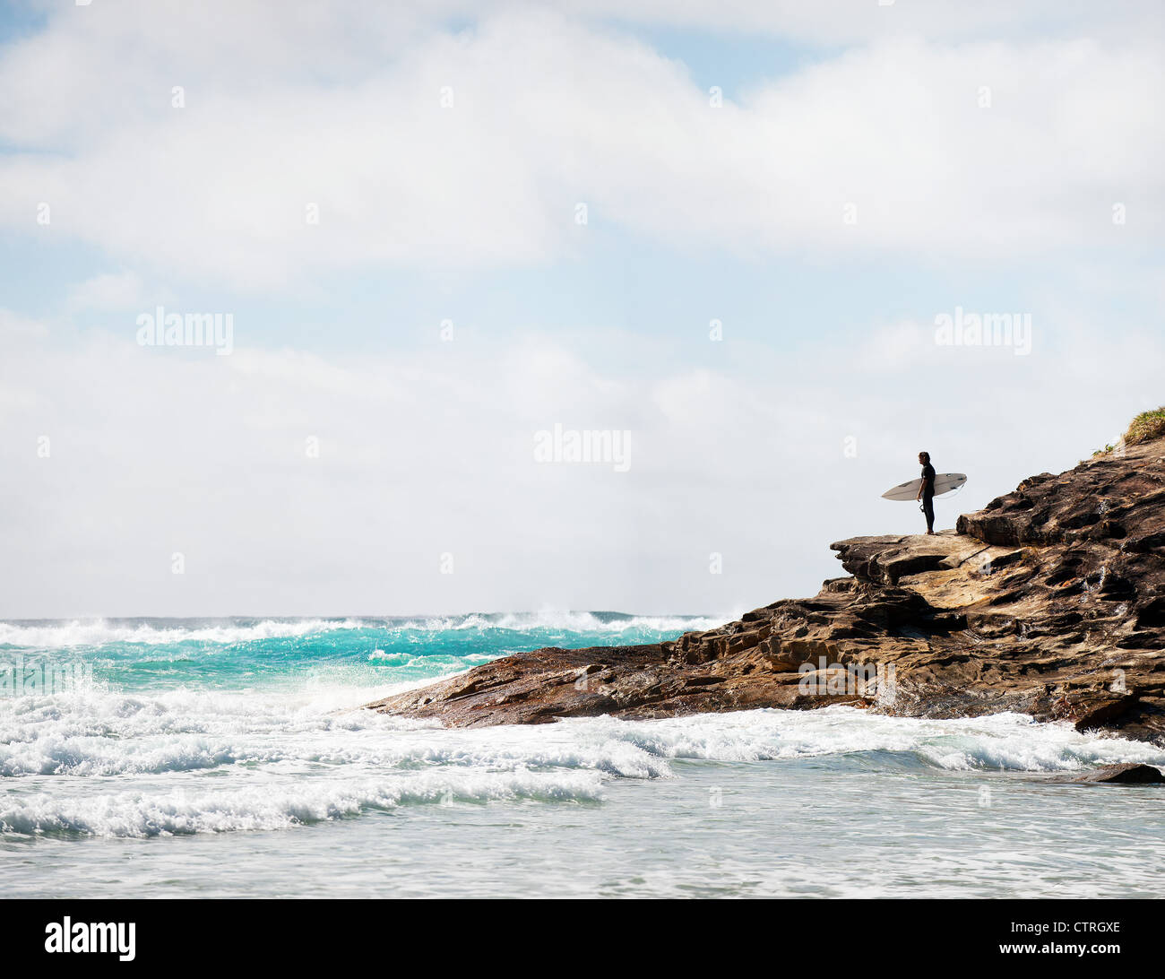 Ein Surfer auf einer Landspitze auf North Stradbroke Island in Queensland, Australien. Stockfoto