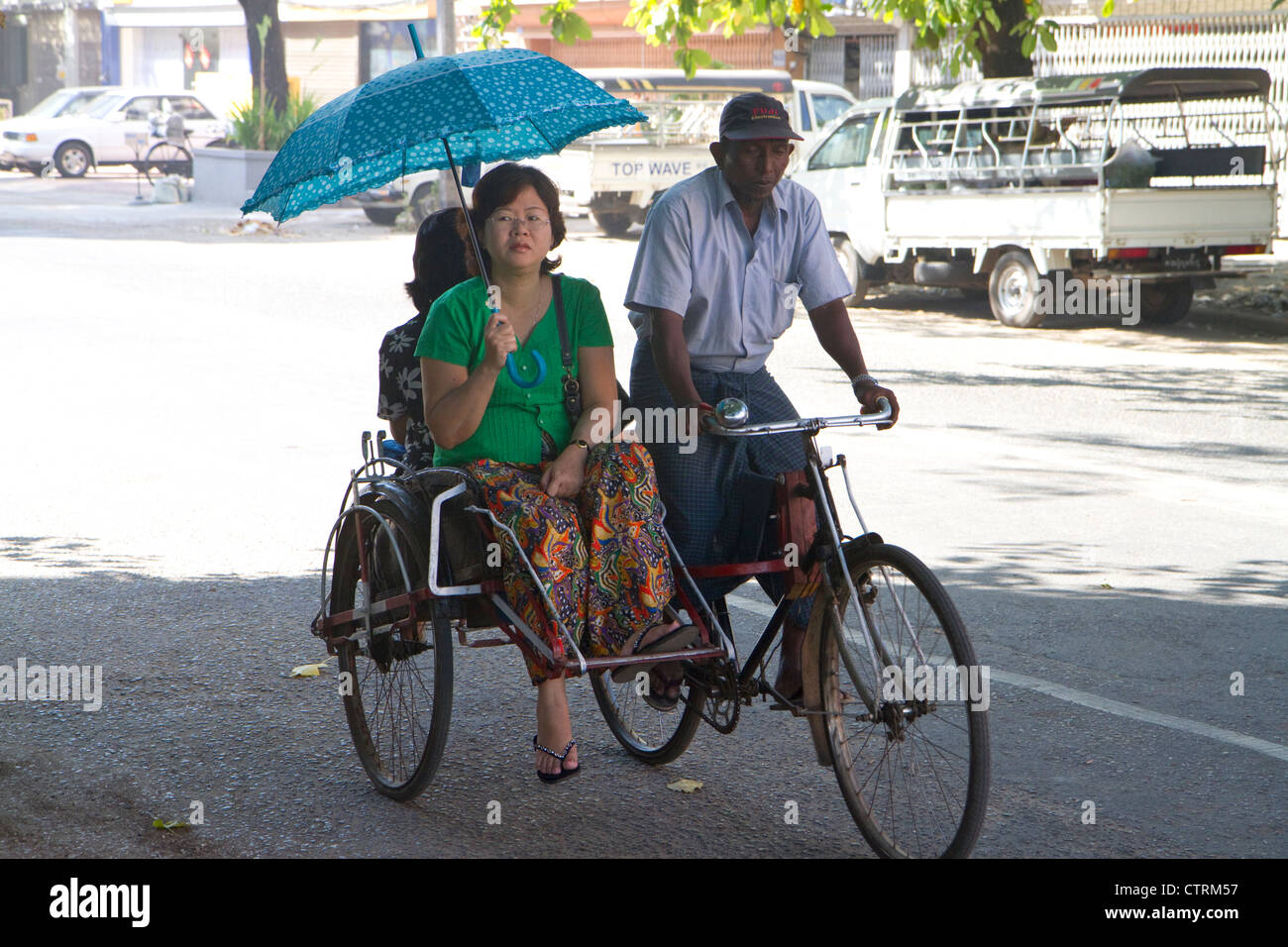 Frau Beschattung selbst während der Fahrt in einer Rikscha in Yangon (Rangoon), Myanmar (Burma) mit einem Regenschirm. Stockfoto