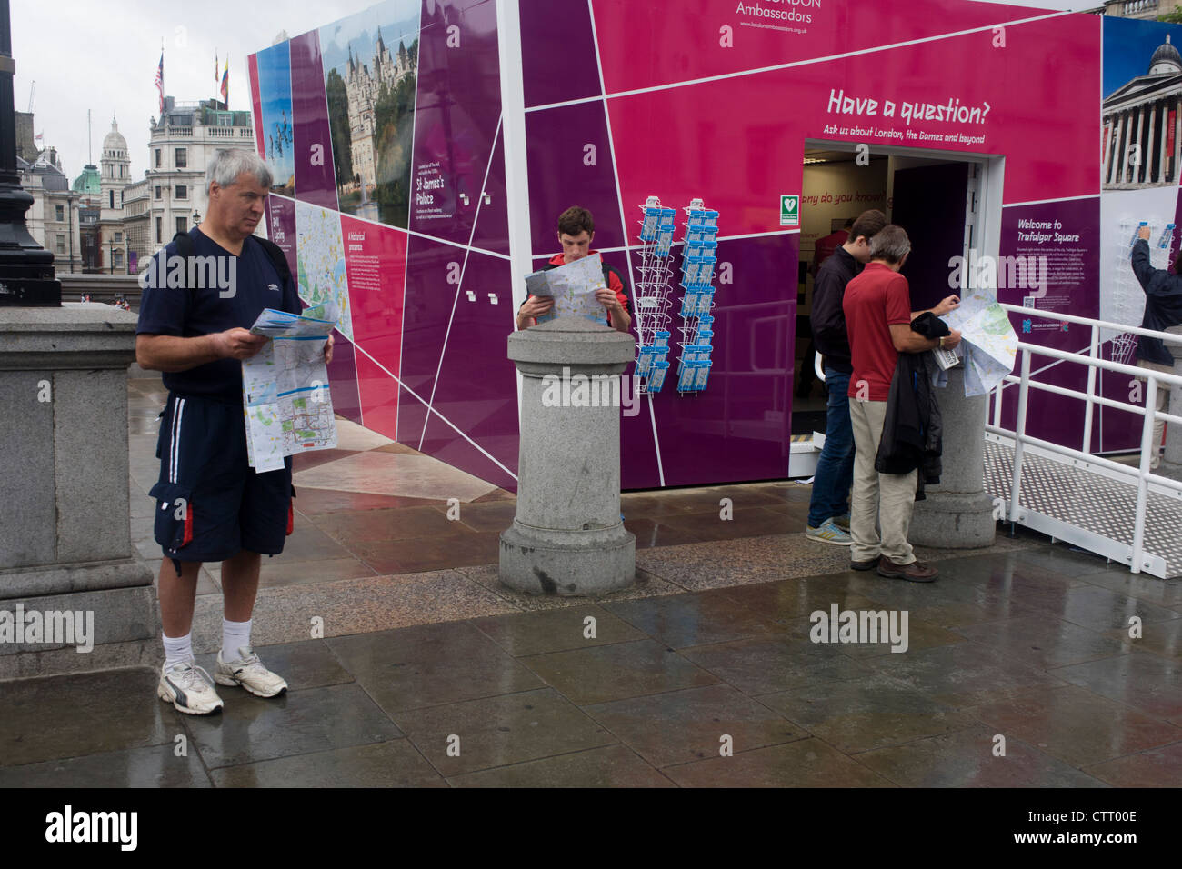 Touristen zu inspizieren Stadtpläne kostenlos zur Verfügung gestellt von Freiwilligen an einem Olympischen Spiele London 2012-Informationen-Kiosk am Trafalgar Square in der Hauptstadt. Stockfoto