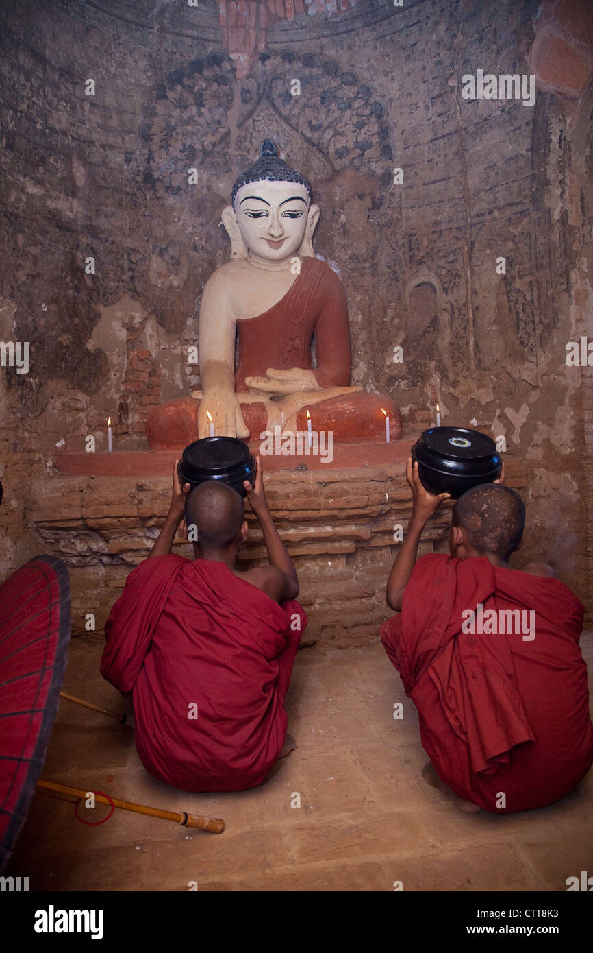 Myanmar, Burma. Bagan. Zwei junge Anfänger Mönche beten vor Buddha-Statue. Stockfoto