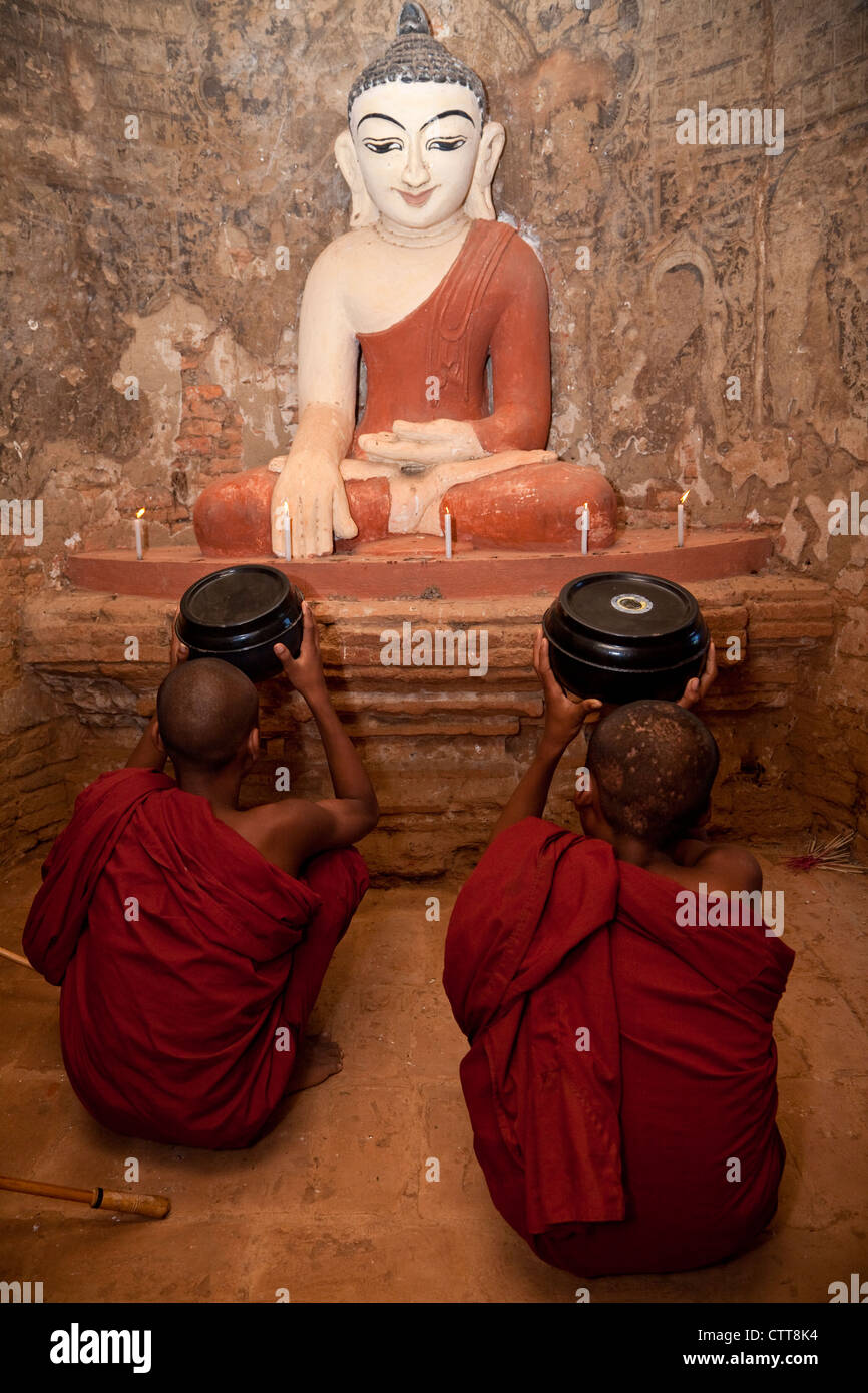 Myanmar, Burma. Bagan. Zwei junge Anfänger Mönche beten vor Buddha-Statue. Stockfoto