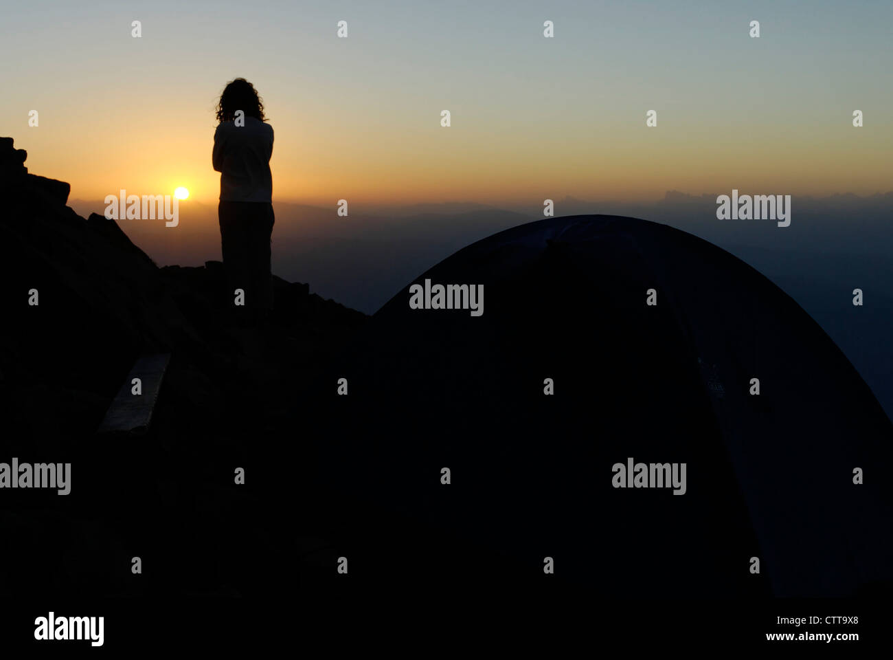 Frau sucht Frau Betrachtet Raummotive Neben Zelt zum Sonnenaufgang in der Nähe von Zelt Stockfoto