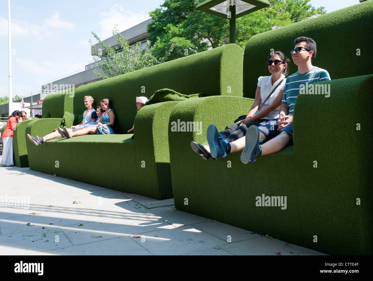 Touristen entspannen Sie sich im riesigen grünen Sofas am Südufer der Themse, London, England Stockfoto