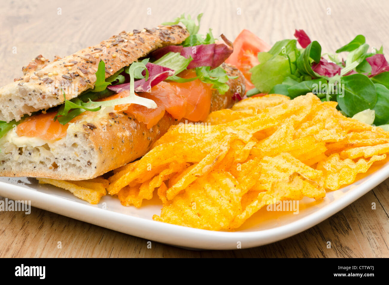 Baguette, gefüllt mit Frischkäse und geräucherter Lachs mit Salat und aromatisierten Chips - Studio gedreht Stockfoto