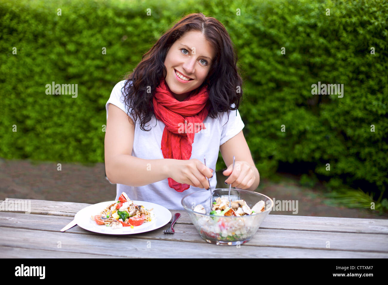 Porträt einer Frau lächelnd während der Vorbereitung einer Schüssel Salat im freien Stockfoto